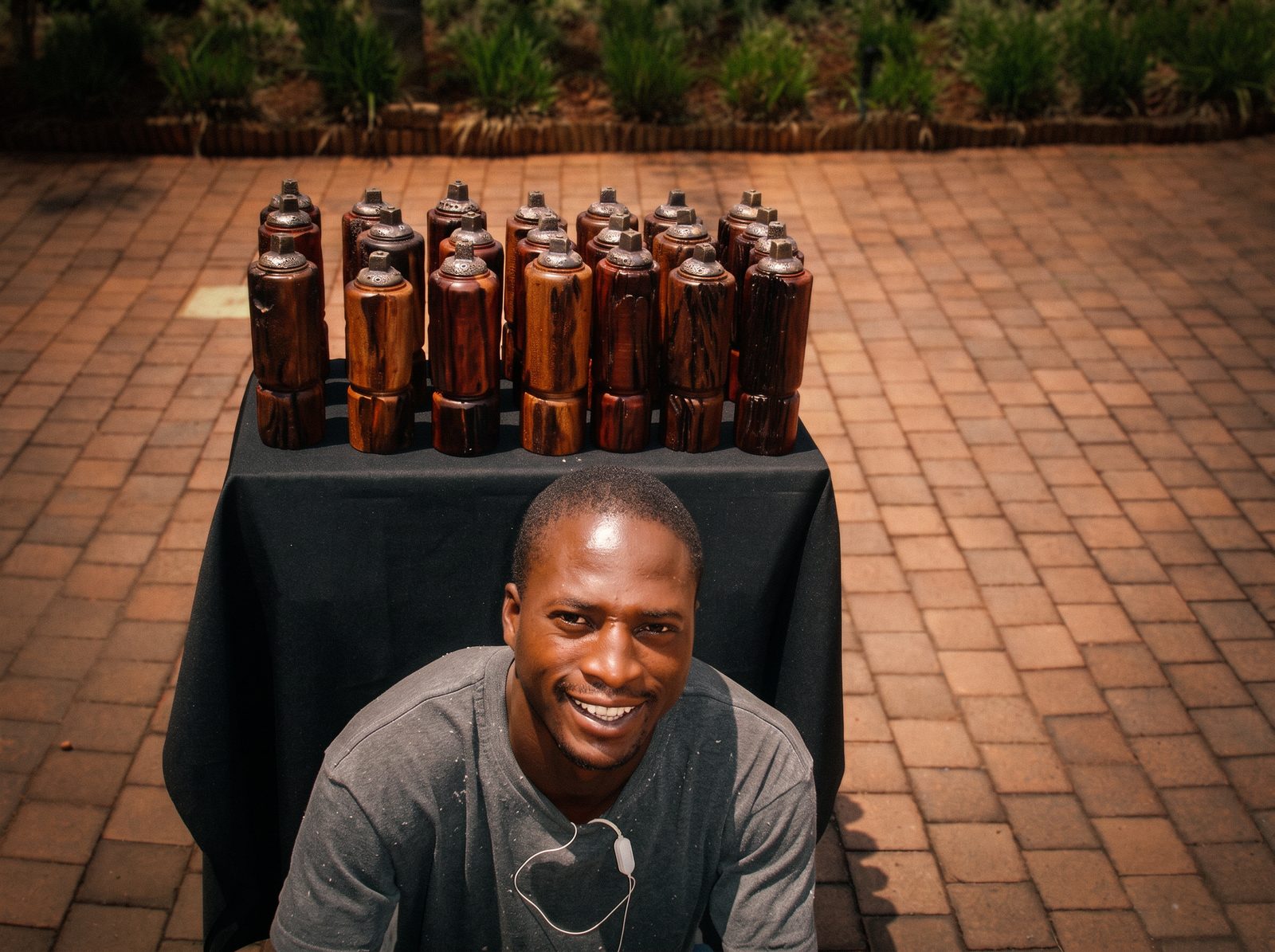 Charlie Letsoalo smiling behind a table of hand-turned wooden pepper mills
